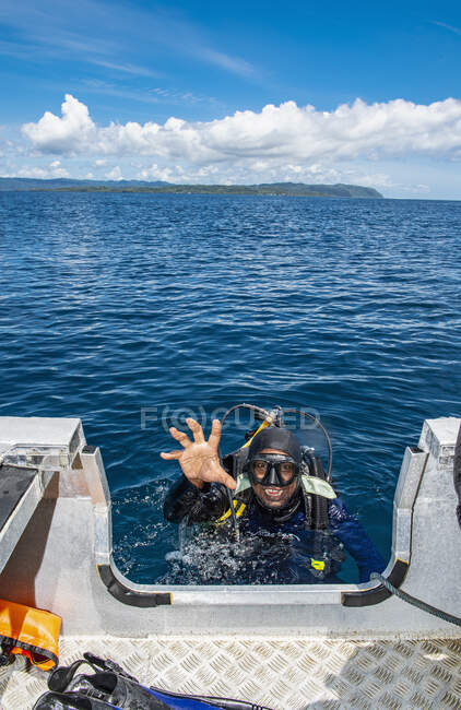 Diver reaching to dingy after returning to the surface in Raja Ampat — Stock Photo