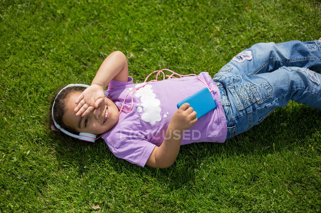 Happy latina girl using smartphone and helmet on sports field — Stock Photo