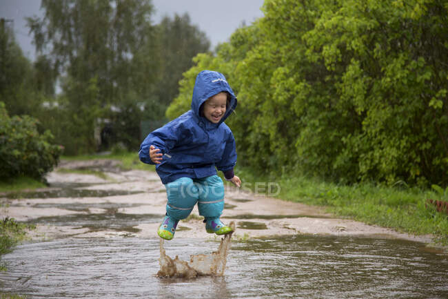 Fille sautant dans une flaque d'eau un jour d'été. — Photo de stock