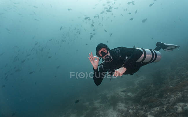 Plongeur avec réservoirs d'air latéraux à Raja Ampat donnant un signal de main — Photo de stock