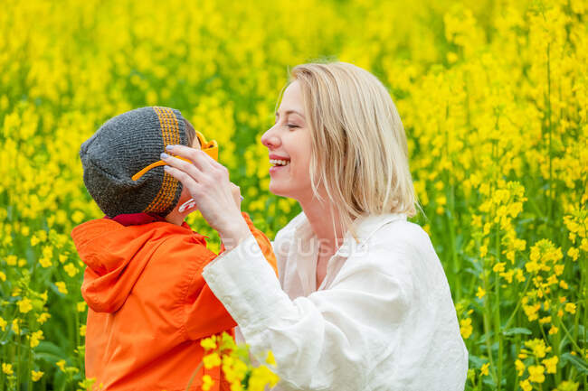 Blonde mère avec un fils sur le champ de colza — Photo de stock