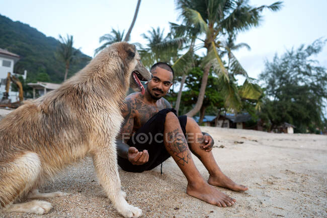 Thai guy on the seashore among the palm trees all in tattoos wit — Stock Photo