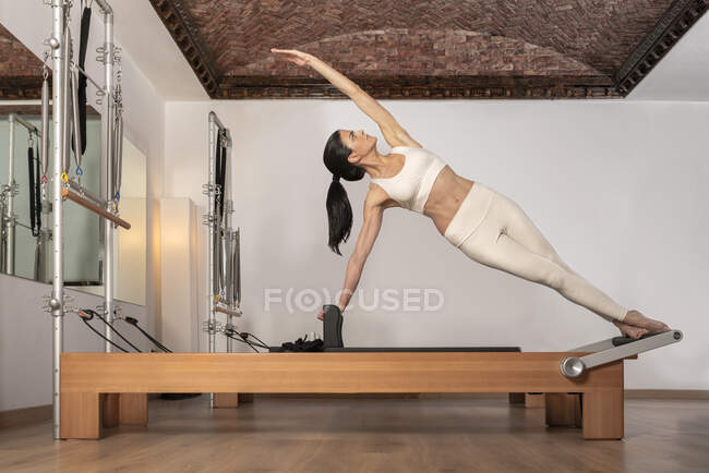 Chica morena haciendo ejercicios de pilates para los abdominales oblicuos - foto de stock