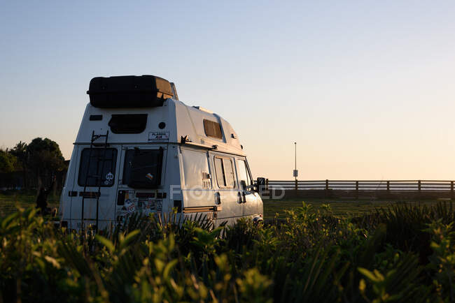Una furgoneta campista en el coas en la puesta del sol - foto de stock