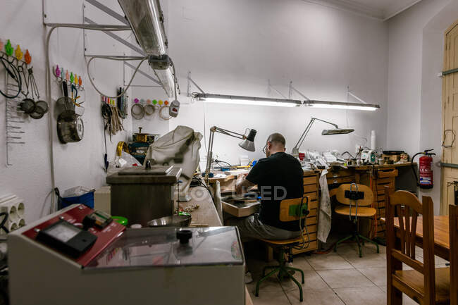 Ювелирная мастерская с мужчиной, работающим на заднем плане. Общая плоскость — стоковое фото