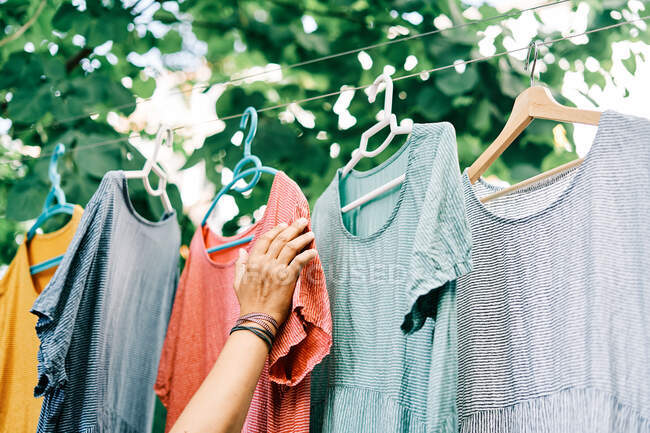 Colorful clothes hanging on hangers on the clothesline in the home garden — Stock Photo