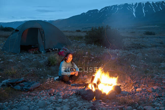 Frau sitzt am Lagerfeuer in Island — Stockfoto