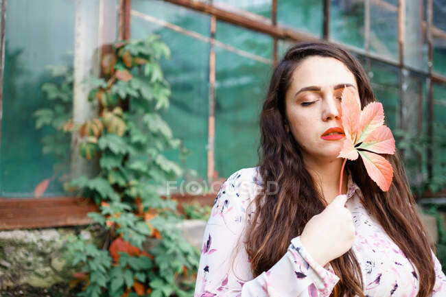 Bella ragazza che tiene una foglia di uva selvatica vicino al suo viso — Foto stock