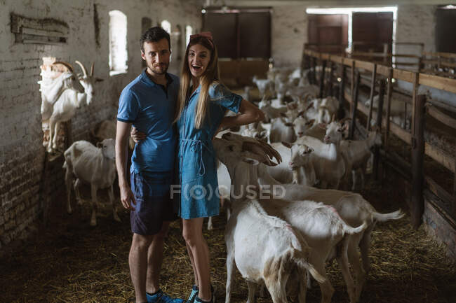 Chica y chica de pie en la granja de cabras - foto de stock