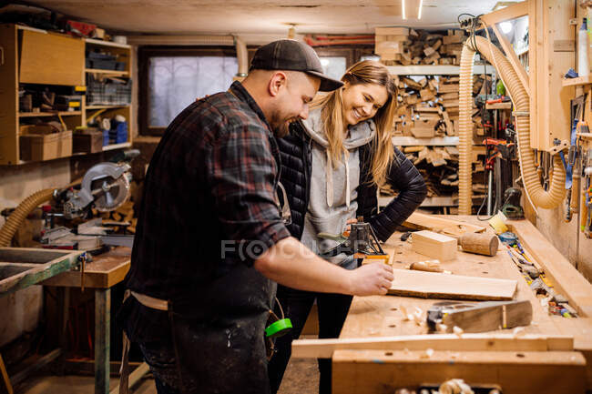 Carpinteiro realiza treinamento em sua oficina para mulher jovem — Fotografia de Stock