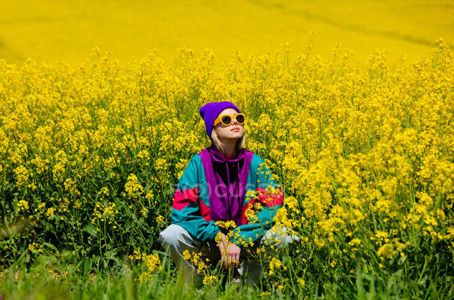 Chica con estilo en 90 's chándal en campo de colza - foto de stock