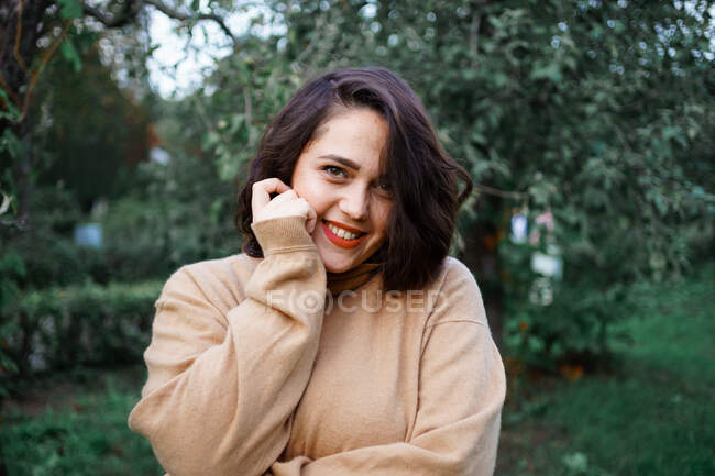 Hermosa chica con lápiz labial rojo en el jardín - foto de stock