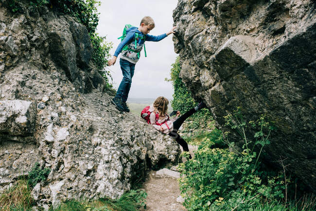 Niños escalando en las rocas en el castillo de Corfe explorando el campo - foto de stock