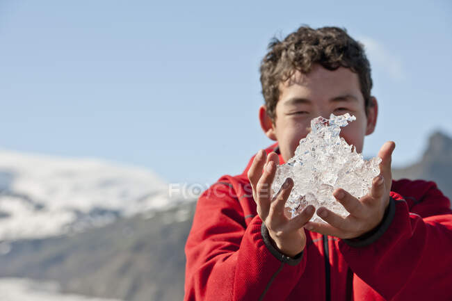 Мальчик-подросток держит лёд из лагуны ледников в Исландии — стоковое фото