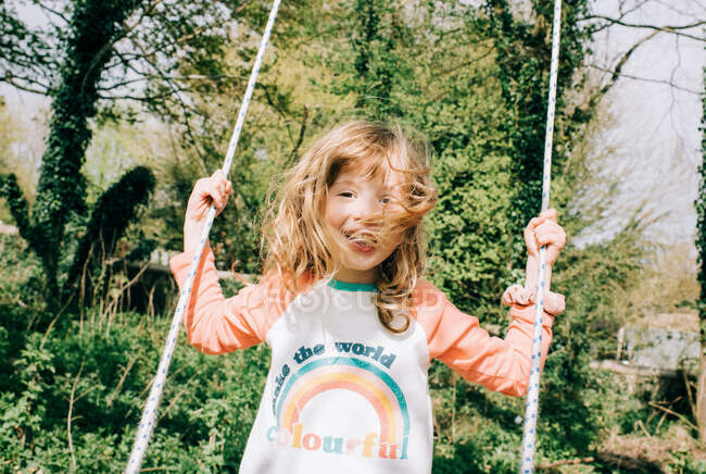 Молода дівчина з радістю плаває на гойдалці в прекрасному парку в Англії. — стокове фото