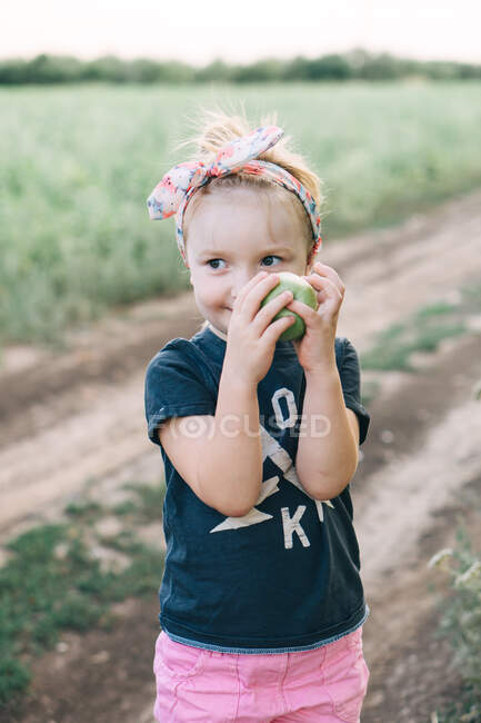 Симпатичная девушка держит в руках зеленое яблоко — стоковое фото