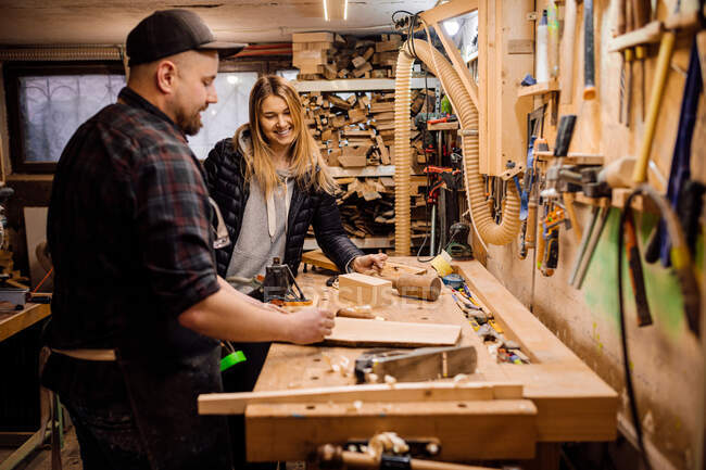 Carpenter communicates with woman customer in his workshop — Stock Photo