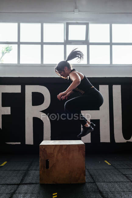 Mujer atlética saltando en la caja del gimnasio para el entrenamiento - foto de stock