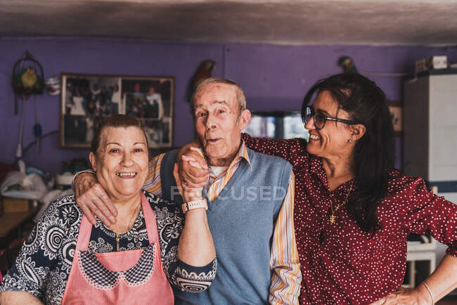 Retrato de una hija de mediana edad y sus padres ancianos abrazándose y sonriendo. - foto de stock