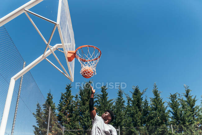 Портрет африканского американца, прыгающего в корзину, чтобы отбить мяч. Играть в баскетбол на городской площадке. — стоковое фото