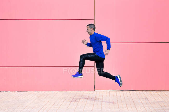 Uomo sportivo che si esercita sulla parete fucsia — Foto stock