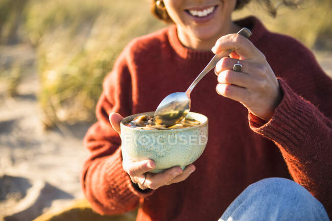 Junge Frau genießt Suppe, während sie allein am Strand campt — Stockfoto