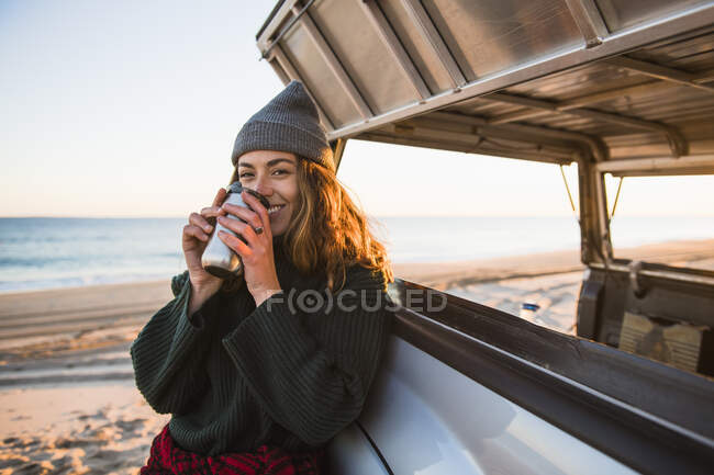 Junge Frau mit Tasse Kaffee am Strand — Stockfoto
