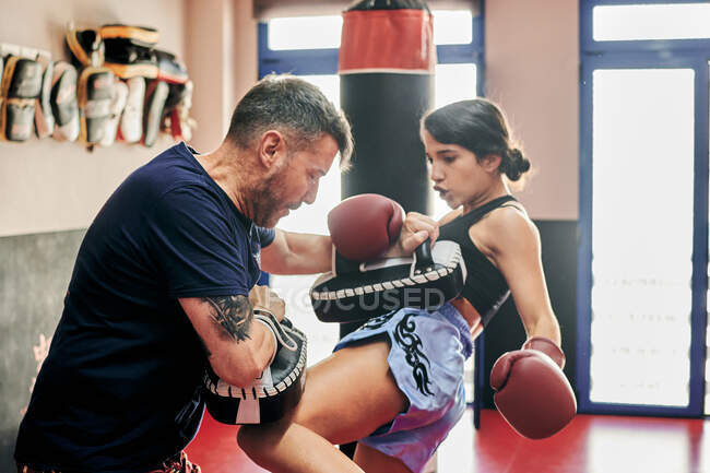 Junge Frau trainiert mit ihrem Muay Thai Trainer in einem Fitnessstudio — Stockfoto
