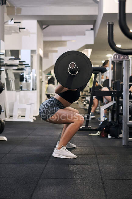 Jovem mulher levanta pesos em um ginásio — Fotografia de Stock