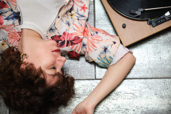 Hipster girl couchée sur le sol et écoutant un disque vinyle sur une platine — Photo de stock