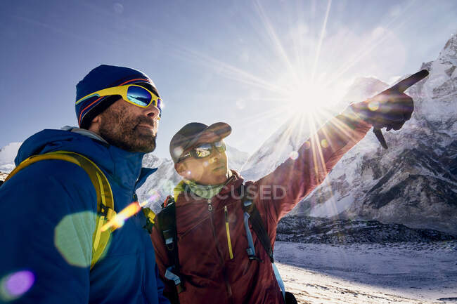Sherpa y guía mirando a la distancia con el Monte Everest - foto de stock