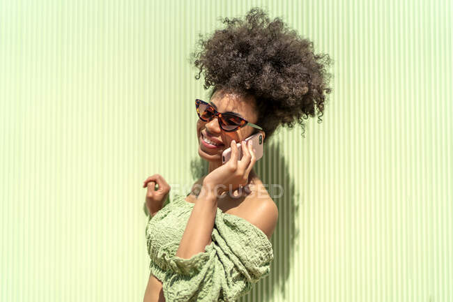 Жінка з афро волоссям розмовляє зі свого смартфона — стокове фото