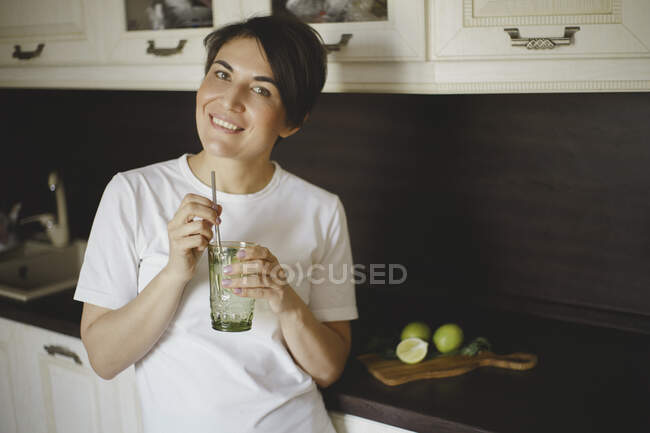 Une femme souriante boit un cocktail sans alcool avec de la paille d'acier réutilisable — Photo de stock