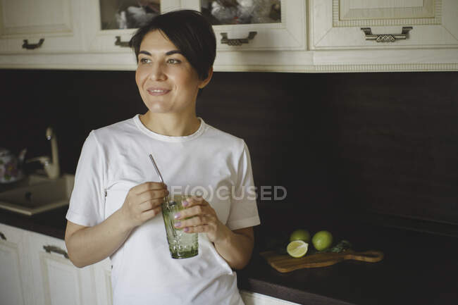 Вид усміхненої жінки п'є безалкогольний коктейль з багаторазовою соломою — стокове фото