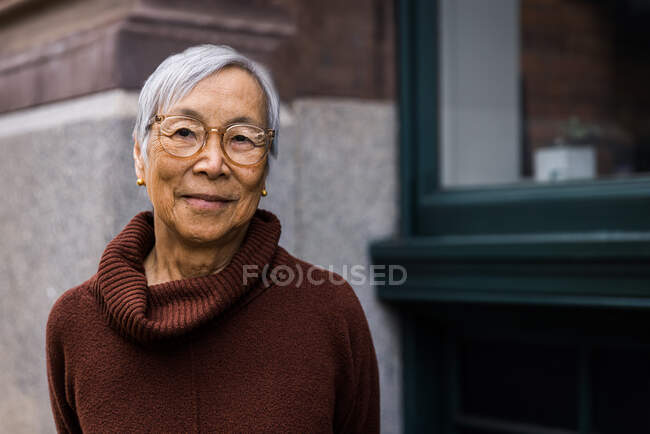 Smiling senior woman wearing eyeglasses standing in city — Stock Photo