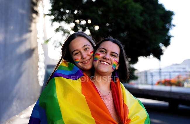 Beautiful lesbian couple having fun in the street with a lgtb flag — Stock Photo
