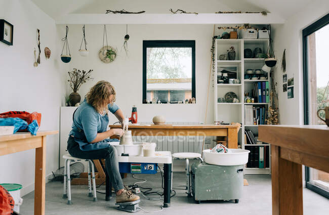 Woman spinning clay on a pottery wheel in her home studio office in UK — Stock Photo