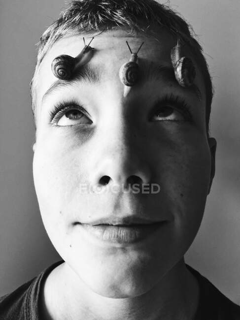 Ein Junge mit drei Schnecken im Gesicht blickt auf — Stockfoto