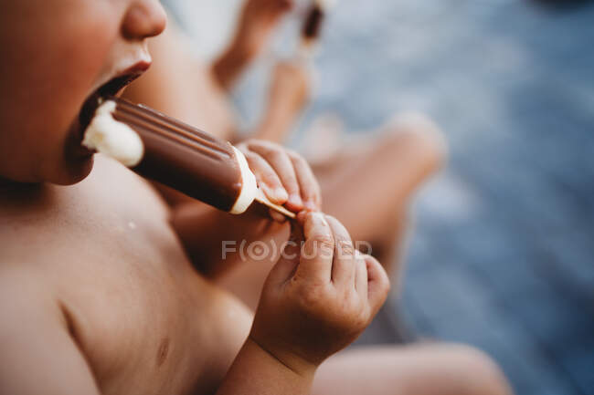 Крупним планом дитячі руки тримають і їдять шоколадний вершковий віск — стокове фото