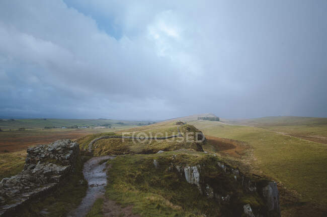 Un paisaje sin fin llena la escena mientras se encuentra en el camino del Muro de Adriano en el Reino Unido. - foto de stock