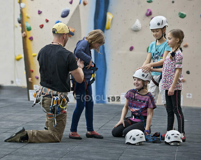 Climbing coach helps girl putting climbing harness — Stock Photo