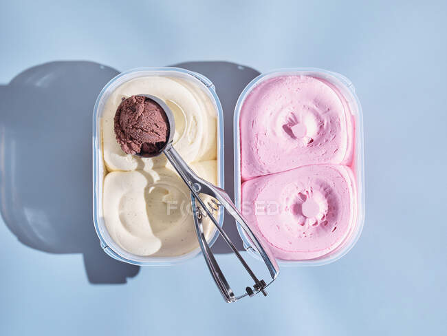 Due vasche gelato e uno scoop isolato su fondo chiaro, con ombre — Foto stock