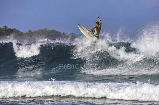 Mann mit Surfbrett surft auf Meereswelle gegen klaren Himmel — Stockfoto