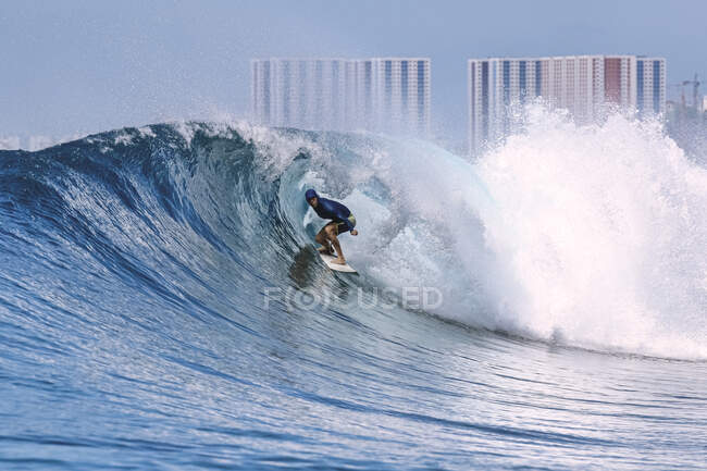Hombre con tabla de surf surfeando en ola de mar contra cielo despejado Hombre con tabla de surf surfeando en ola de mar contra cielo despejado - foto de stock