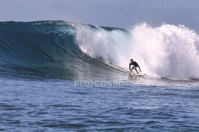 Hombre con tabla de surf surfeando en ola de mar contra cielo despejado Hombre con tabla de surf surfeando en ola de mar contra cielo despejado - foto de stock