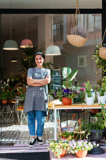 Флорист, стоящий у двери ее цветочного магазина — стоковое фото