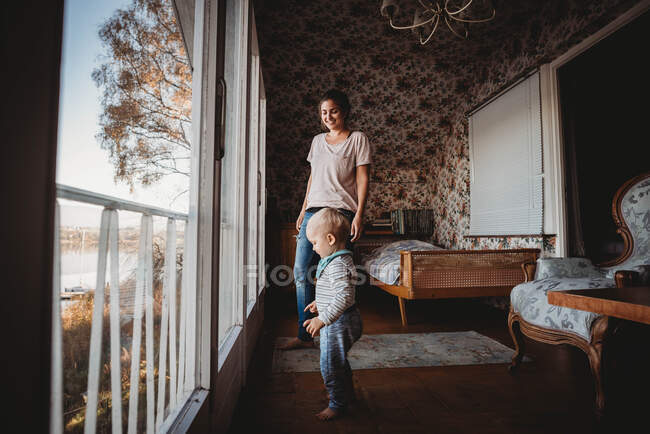 Madre e hijo en dormitorio vintage con papel pintado de flores - foto de stock