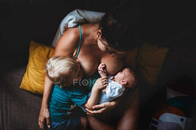 Mamá tándem amamantando bebé recién nacido y niño pequeño - foto de stock