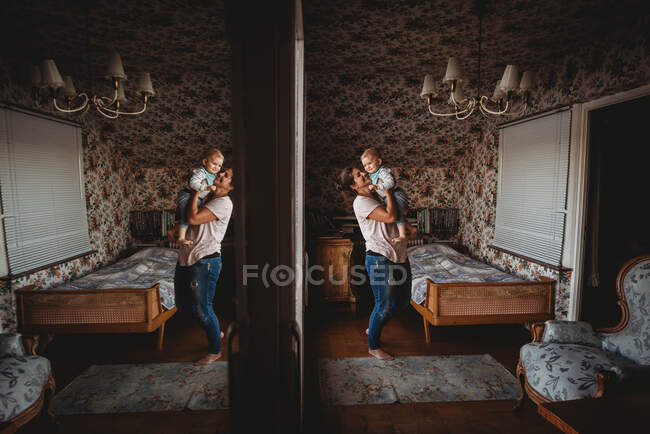 Maman tenant bébé dans une chambre vintage avec miroir réfléchissant — Photo de stock