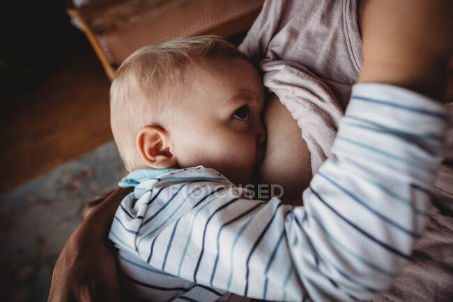 Gros plan sur l'allaitement d'un bébé garçon dans une lumière agréable — Photo de stock